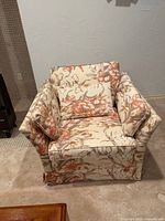 Front angled view of floral armchair showing pattern and cushions