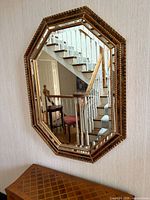 Full view of octagonal gold mirror hung on wall