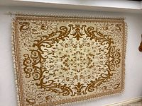 Full view of ivory and gold tapestry hanging on wall