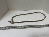Full view of necklace laid next to ruler showing length
