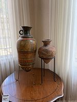 Front view of painted amphora and terracotta jar on stands