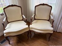 Front view of both cream upholstered French Provincial armchairs