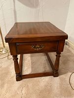 Front view showing overall table, turned legs, stretcher, drawer with brass pull
