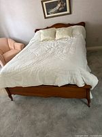 Full view of queen bed with bedding, headboard and footboard visible