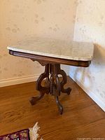 Full view of marble-top side table in corner