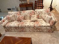 Full view of floral sofa showing pattern, cushions, skirted base