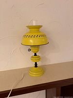 Full view of yellow oil-style electric table lamp with glass chimney