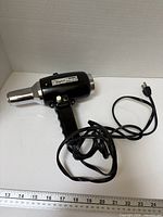 Full view of hair dryer with cord and ruler for scale