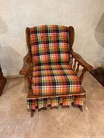 Front view of glider chair showing wood frame, plaid upholstery, skirted base