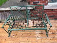 Front view of green wrought iron loveseat frame on deck