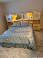 Full view of queen bed with mirrored storage headboard and bedding