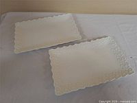 Two white rectangular serving plates with embossed edges
