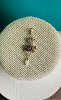 Front view of 10K gold pendant on display stand showing ruby, seed pearls and pearl drop