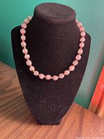 Full view of pink blown glass bead necklace on black display bust