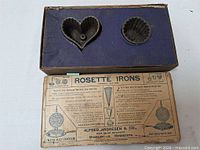 Open box showing two cast iron molds seated in blue insert and exterior of box with instructions