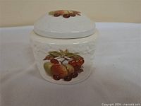 Front view of white porcelain tea caddy with fruit motif and lid