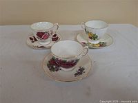 Three bone china teacup and saucer sets on table