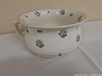 Side view of chamber pot showing floral pattern and handle