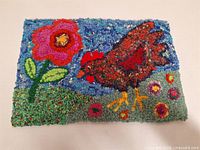 Full view of hand-hooked wool artwork depicting chicken and flower