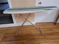 Full view of metal ironing board standing open