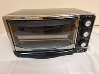 Front view of Oster countertop toaster oven showing glass door, controls, rack inside