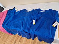 Overall view of two blue tops and glimpse of pants with tags