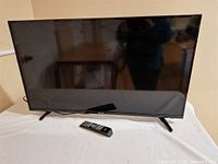 Front view of Sharp LED TV on stand with remote placed in front
