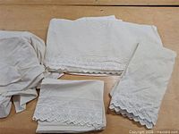 Full sheet set laid out: two pillowcases, fitted sheet, flat sheet, embroidery visible