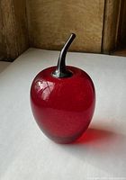 Front view of red glass apple paperweight with dark stem