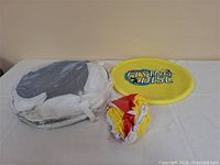 All three items on table: yellow flying disc, mesh case item, deflated beach ball