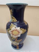 Full view of cobalt blue ceramic vase with raised floral motif