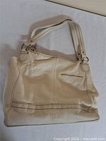 Full view of cream leather handbag front with straps displayed