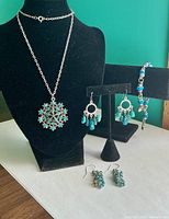All jewellery pieces displayed on stands: necklace, bracelet, two earring pairs
