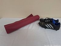 Overall view of red yoga mat and pair of Adidas cleats
