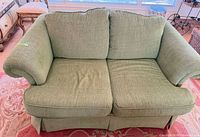 Front view of green loveseat showing cushions and skirt