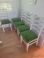 All five white ladderback chairs lined against wall