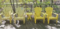 Front view of four yellow Adirondack chairs with side table