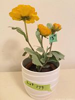 Full view of artificial yellow flowers in white ceramic planter, height note 13 inches visible