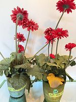 Two artificial gerbera daisy arrangements in green pots