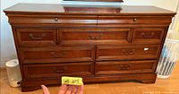 Front view of cherry wood dresser showing nine drawers and hardware
