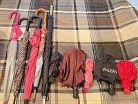 Full lot showing all five stick umbrellas and five compact umbrellas aligned on bedspread