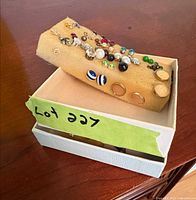 Closed jewelry box with sponge insert showing multiple stud earrings attached