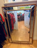 Full view of rectangular framed mirror leaning against wall