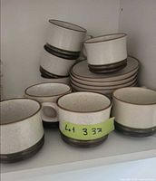 Stacked speckled cream Denby cups and saucers in cupboard