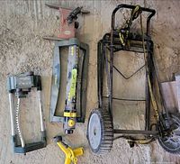 Foldable hand truck, sprinklers laid beside it on concrete floor