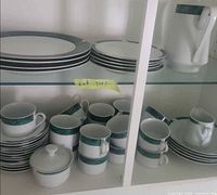 Cabinet view showing plates, cups, sugar bowl, coffee pot