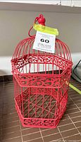 Full view of red hexagonal metal birdcage with tag attached