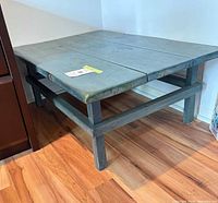 Full view of blue-gray wooden coffee table showing plank top and stretcher frame
