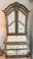 Full view of secretary desk showing arched top, doors, drop front, lower drawers, floral painting