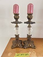 Front view of both ornate brass and glass candle holders with pink candles
